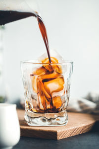 Close-up of jug pouring drink in glass on table