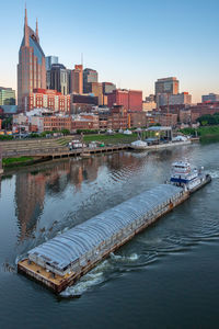 Boats in river by buildings in city against clear sky