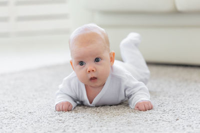 Portrait of cute baby boy lying on floor
