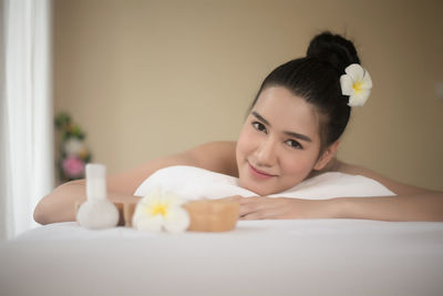 Portrait of smiling young woman lying on massage table in spa