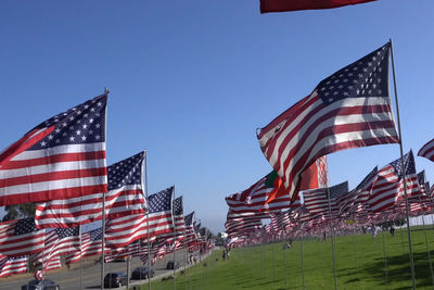 Low angle view of flags against clear blue sky