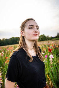 Portrait of beautiful young woman on field against sky
