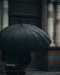 Close-up of man holding umbrella during rainy season