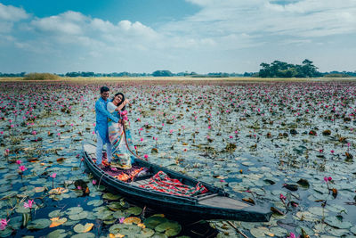 View of people standing in waterlily pond against sky