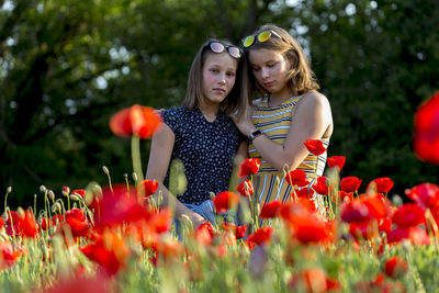 Siblings standing amid red flowers
