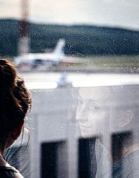 Portrait of woman looking through wet window