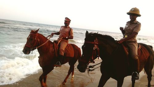 Men riding horses on beach