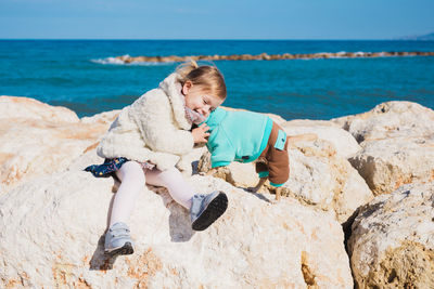 Portrait of woman sitting on rock at beach