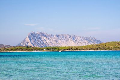 Scenic view of sea and mountains against blue sky