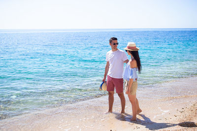 Full length of friends standing on beach