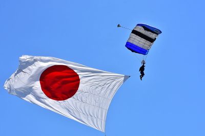 Low angle view of paraglider paragliding with japanese flag