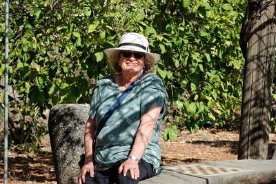 Portrait of young woman sitting on tree trunk