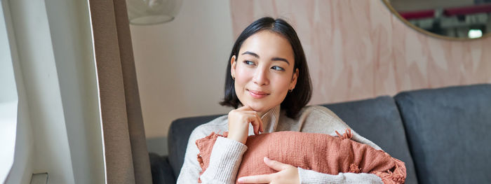 Portrait of young woman sitting on sofa at home