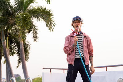 Full length of man standing on palm tree against clear sky