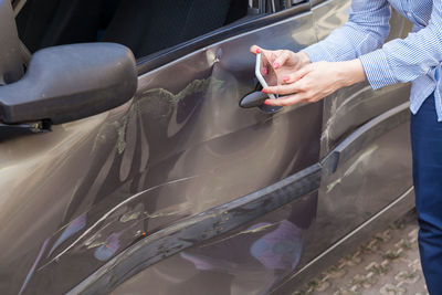 Midsection of woman holding umbrella in car