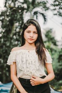 Portrait of happy girl standing against tree