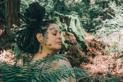 Portrait of young woman looking away in forest