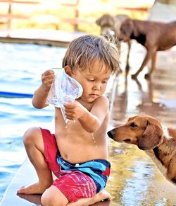 Rear view of boy with dog in water