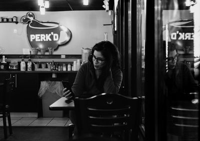 Woman using mobile phone while sitting in cafe