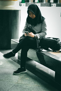 Full length of man using phone while sitting on seat