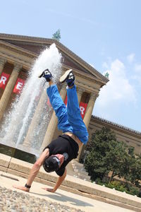 Full length of man performing handstand against historic building