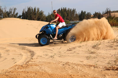 Portrait of man driving quadbike on sand