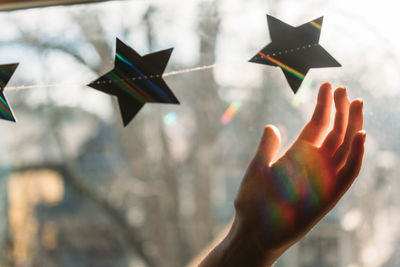 Cropped hand touching star shape on window