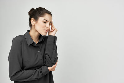 Young woman looking away while standing against white background