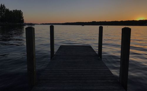 Pier over lake against sky during sunset