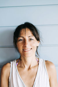 Portrait of smiling woman standing against wall