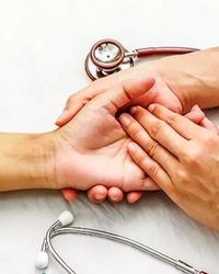 High angle view doctor and patient holding hands on table