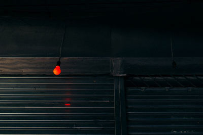 Low angle view of illuminated light bulb hanging in darkroom