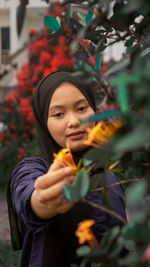 Portrait of woman wearing hijab holding flower