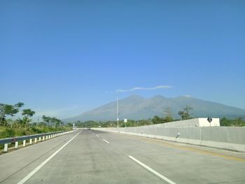 Empty road against clear blue sky