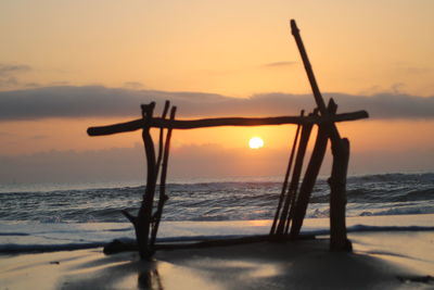 Silhouette tree on beach against sky during sunset