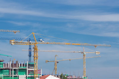 Cranes at construction site against sky