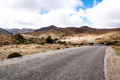 Scenic view of road by mountains against sky