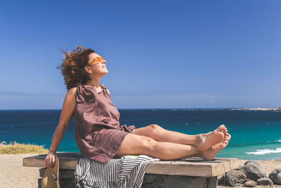 Side view of woman sitting at beach