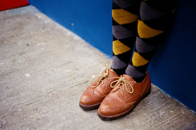 Low section of person wearing shoes standing by wall