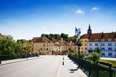 Road amidst buildings against blue sky