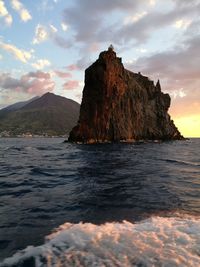 Rock formation in sea against sky during sunset