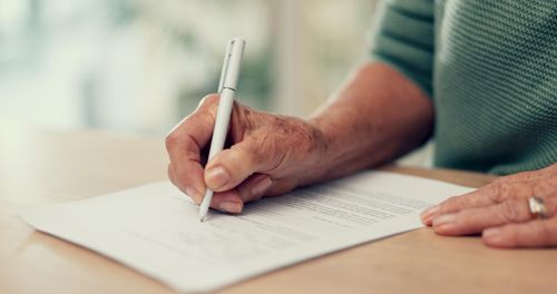 Midsection of man writing in book