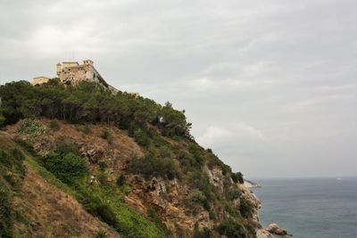 Scenic view of sea by cliff against sky