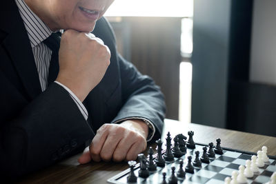 Midsection of businessman playing chess at table in office
