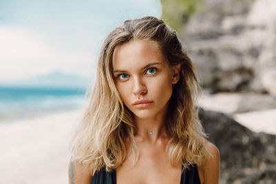 Portrait of young woman standing at beach