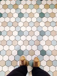 Low section of man wearing golden shoes on flooring