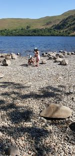 People sitting on beach by sea against mountain