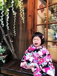 Girl looking away while sitting on plant