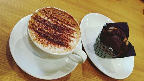 High angle view of cappuccino next to muffin