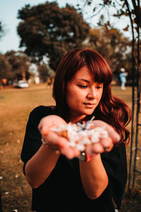 Portrait of young woman holding sunglasses